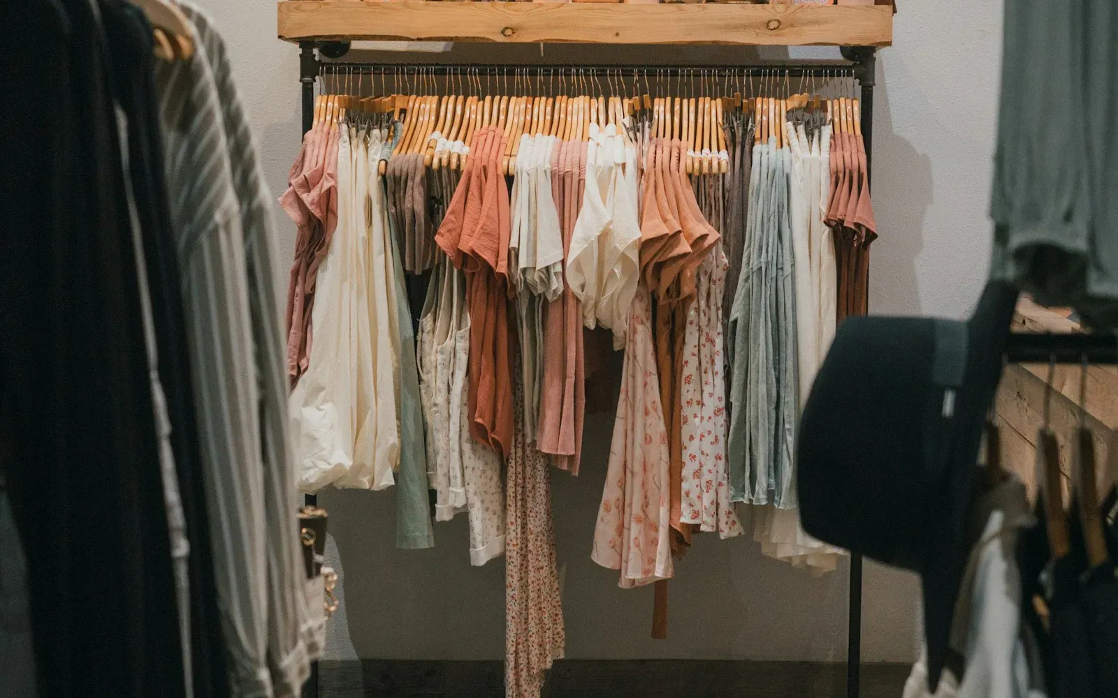 Kleiderstange mit Blusen und Kleidern in Pastelltönen in einer Boutique