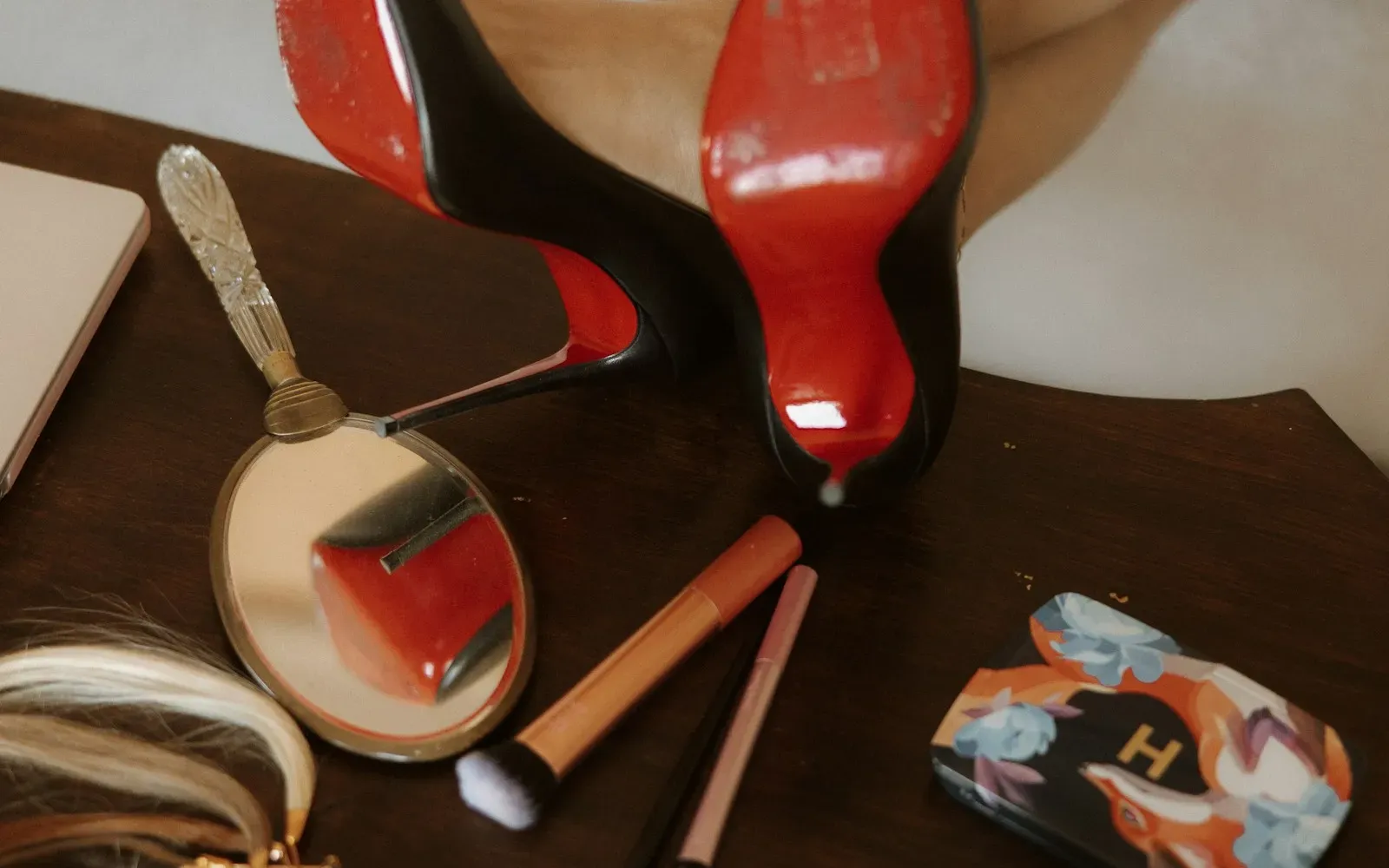 Rote Pumps, Handspiegel und Make-up-Pinsel auf einem Holztisch